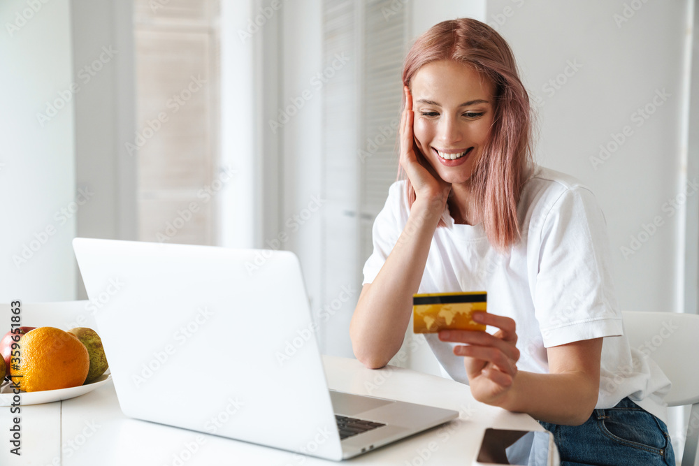 Photo of cheerful woman working with laptop and holding credit card Photo of cheerful woman working with laptop and holding credit card
