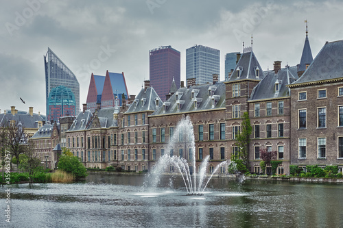 View of the Binnenhof House of Parliament and the Hofvijver lake with downtown skyscrapers in background. The Hague, Netherlands