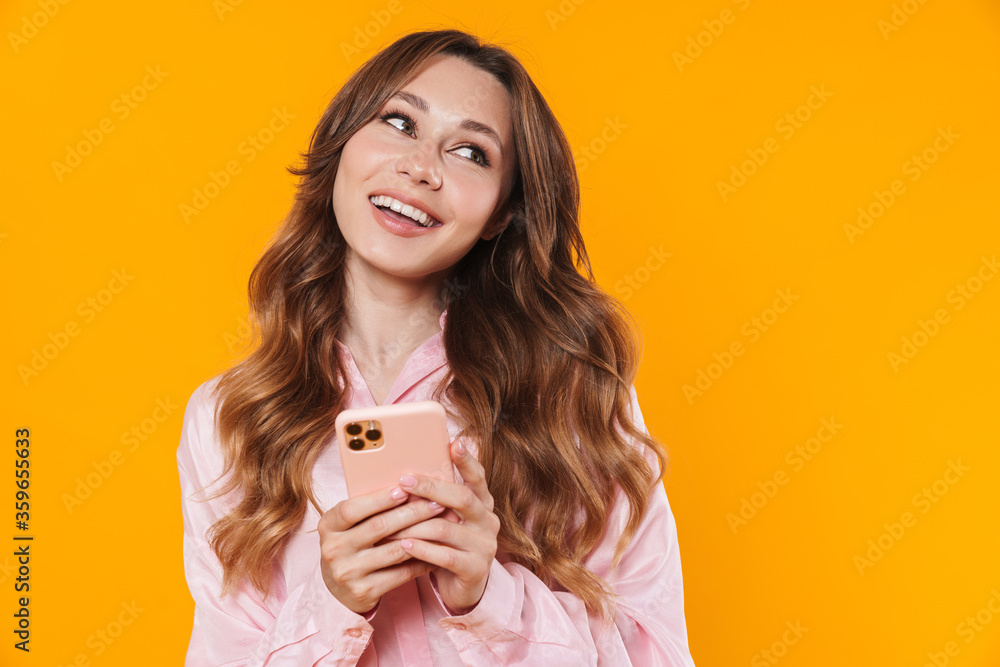 Image of beautiful pleased woman smiling and using mobile phone Image of beautiful pleased woman smiling and using mobile phone