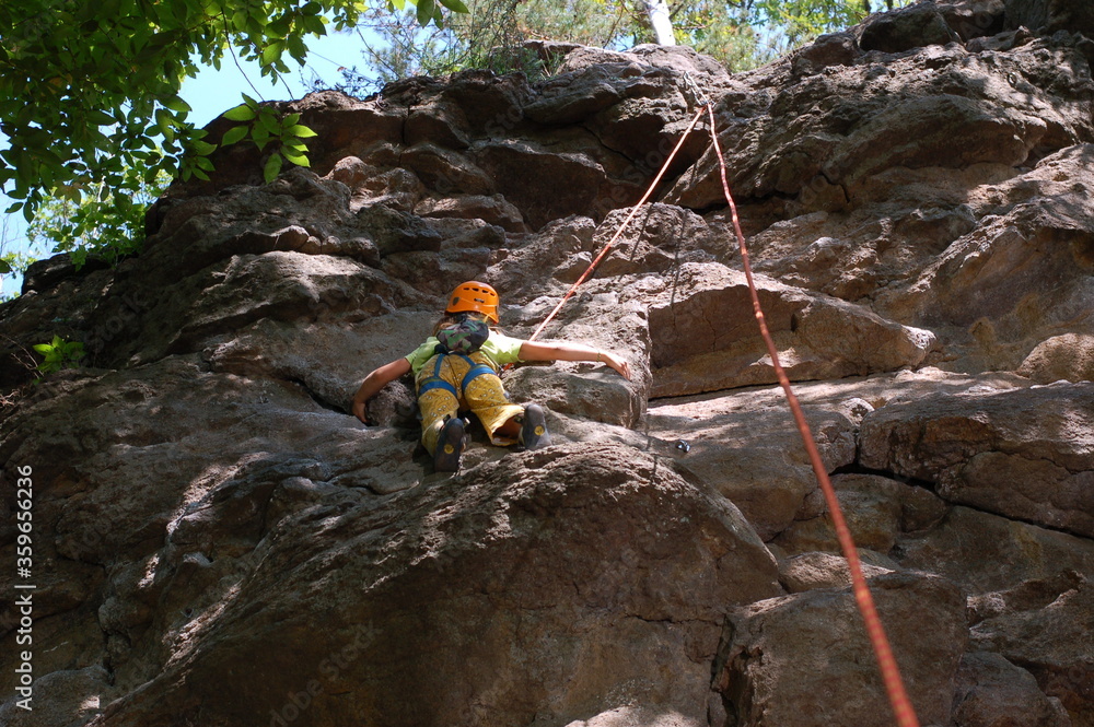 little boy climbs on the rock with rope little boy climbs on the rock with rope