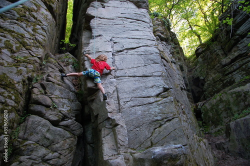 little boy climbs on the rock with rope photo