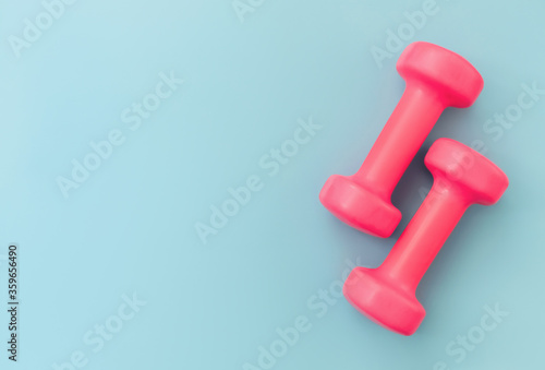 Set of two pink dumbells on blue background. Women fitness concept. Sport and diet. Home workout. Top view. Copy space