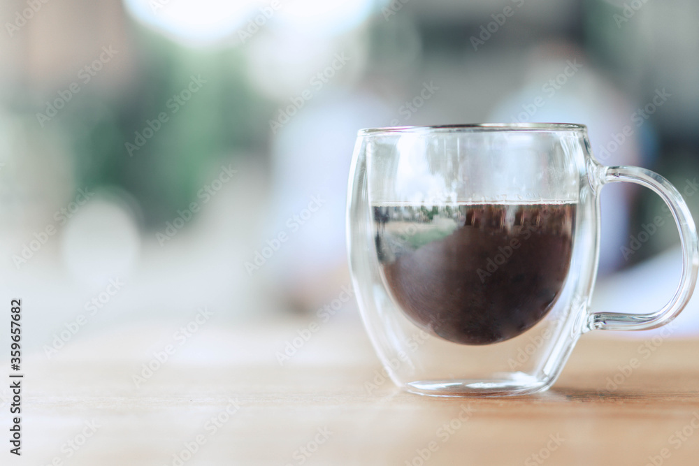 Closeup glass of hot americano coffee on wood table, selective focus, vintage tone Closeup glass of hot americano coffee on wood table, selective focus, vintage tone