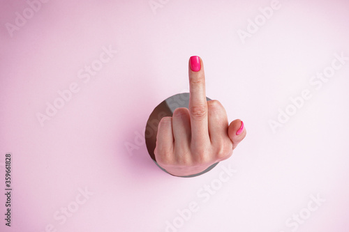 Quadro su tela Middle finger on a pink background, abusive gesture