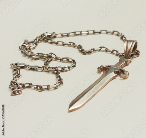Silver pendant in the shape of a sword on an anchor chain, silver set of earrings and rings with natural red garnet stone, pendant in the shape of a lizard with transparent zircon on a white backgroun