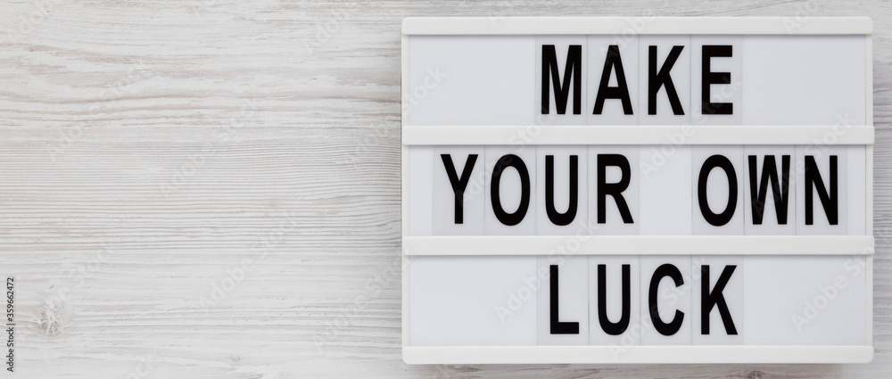 'Make your own luck' on a lightbox on a white wooden surface, top view. Flat lay, from above, overhead. Copy space. 'Make your own luck' on a lightbox on a white wooden surface, top view. Flat lay, from above, overhead. Copy space.