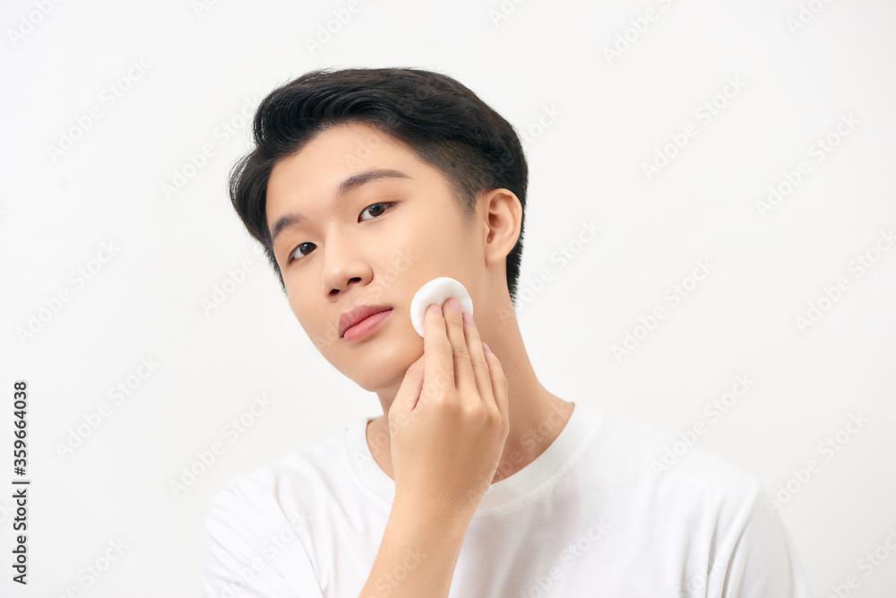 Man cleaning face skin with batting cotton pads over white background Man cleaning face skin with batting cotton pads over white background