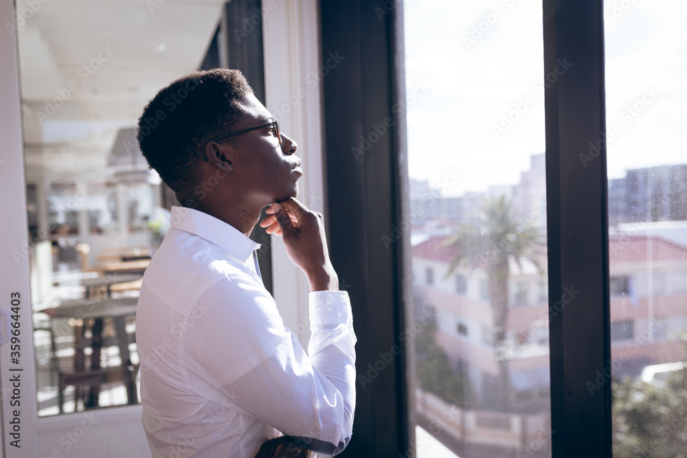Young African American businessman thinking in front of windows Young African American businessman thinking in front of windows