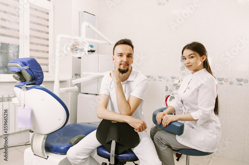 A male dentist and a female assistant are ready to receive a client in the dental office