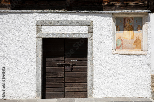 Canza (VCO), Italy - June 21, 2020: An old wooden door and a religius paint at Canza village, Formazza Valley, Ossola Valley, VCO, Piedmont, Italy