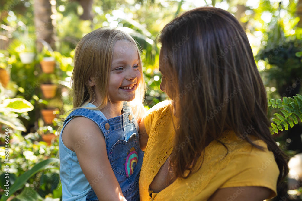 A Caucasian woman and her daughter enjoying time together in a sunny garden A Caucasian woman and her daughter enjoying time together in a sunny garden