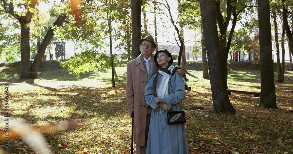 Elegant married couple stands in embraces, admires autumn beauty and talks Elegant married couple stands in embraces, admires autumn beauty and talks