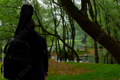 Young man carry guitar bag while walking through the forest