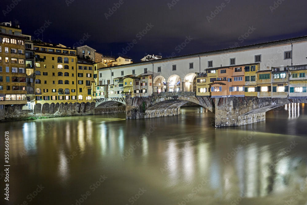 The Medieval stone 'Ponte Vecchio' bridge spanning the River Arno illuminated at night