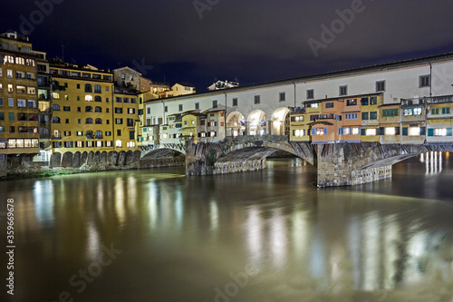 The Medieval stone 'Ponte Vecchio' bridge spanning the River Arno illuminated at night © allan