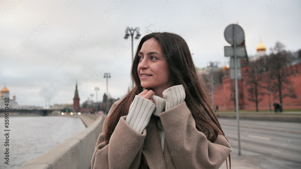 Fototapeta premium A positive girl walks along the promenade and laughs. Person spinning in a circle. Smiling woman walks along the promenade in Moscow. Russia.