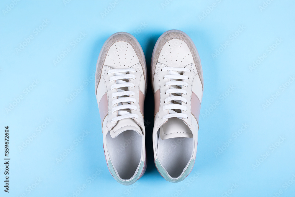 Female sneakers on blue background. Flat lay, top view minimal background. Fashion blog or magazine concept Female sneakers on blue background. Flat lay, top view minimal background. Fashion blog or magazine concept