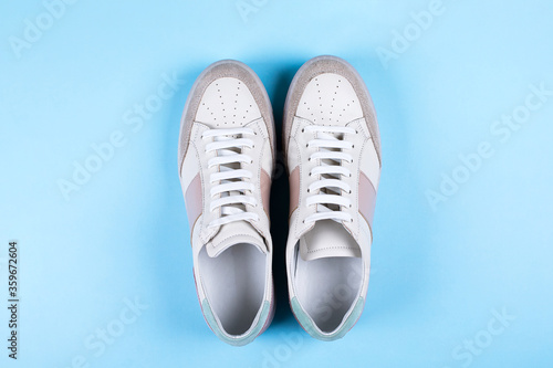 Female sneakers on blue background. Flat lay, top view minimal background. Fashion blog or magazine concept