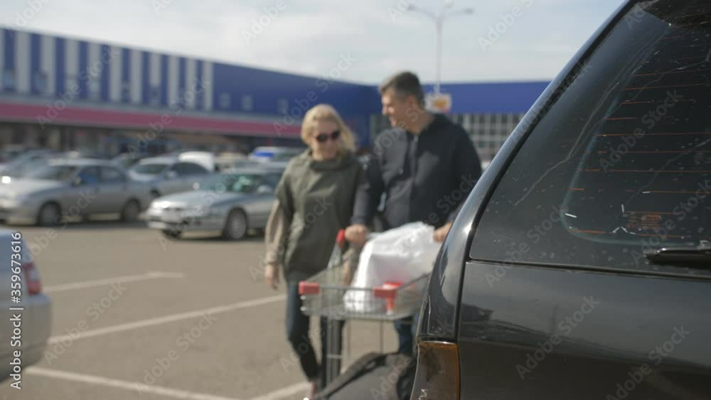 A couple folded shopping from shopping trolleys in the trunk of a car in the Parking lot of the Mall. A couple folded shopping from shopping trolleys in the trunk of a car in the Parking lot of the Mall.