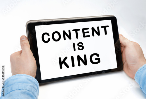 Male hands holding tablet pc with text CONTENT IS KING on white background