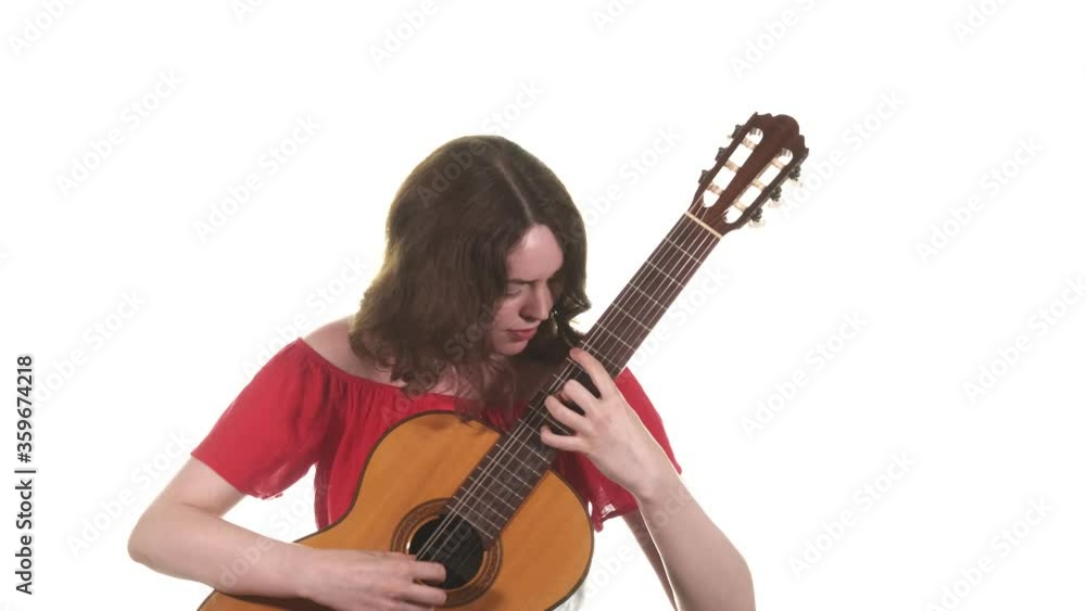 Pretty girl in a red blouse playing the classical acoustic guitar. Medium long shot. Isolated Pretty girl in a red blouse playing the classical acoustic guitar. Medium long shot. Isolated