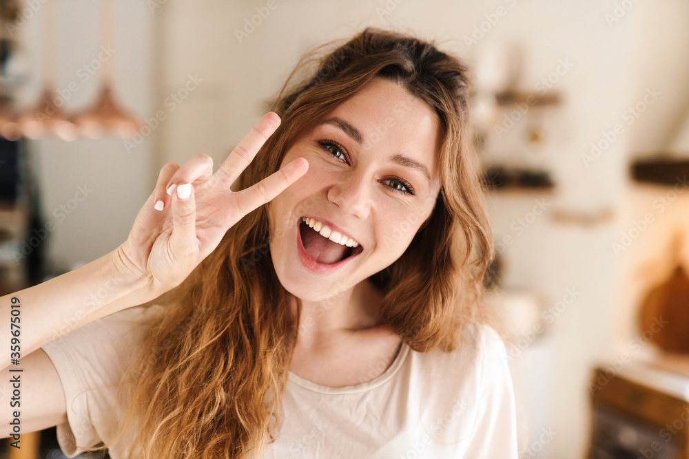 Cheerful lovely girl grimacing while standing in the kitchen Cheerful lovely girl grimacing while standing in the kitchen