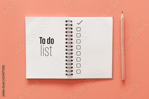 Notebook and pencil with to do list words on pastel color background.