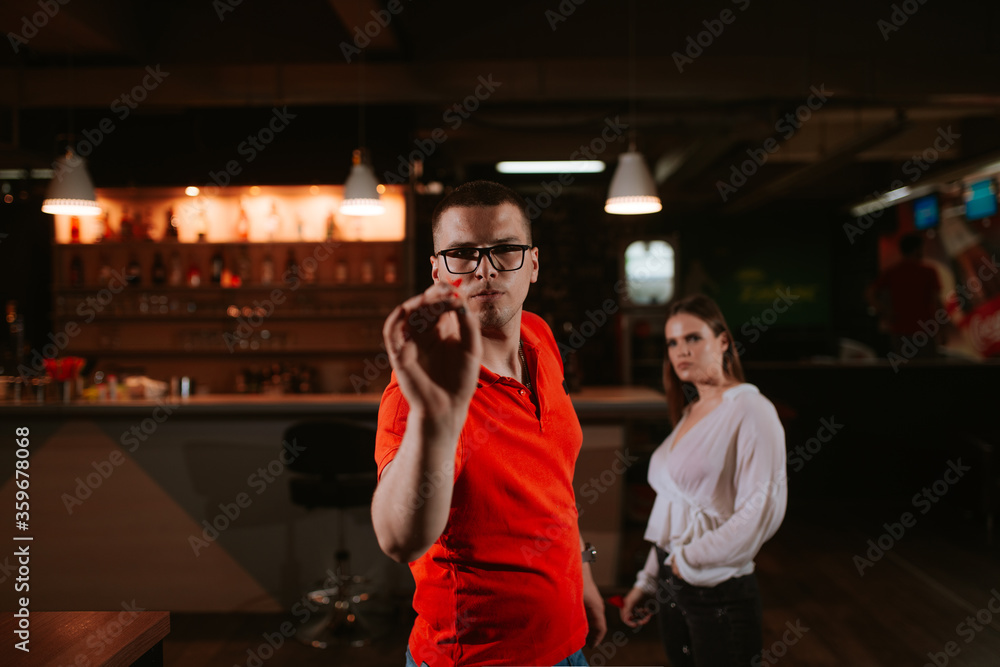 A young beautiful caucasian woman and a man are playing darts. Love and recreation A young beautiful caucasian woman and a man are playing darts. Love and recreation
