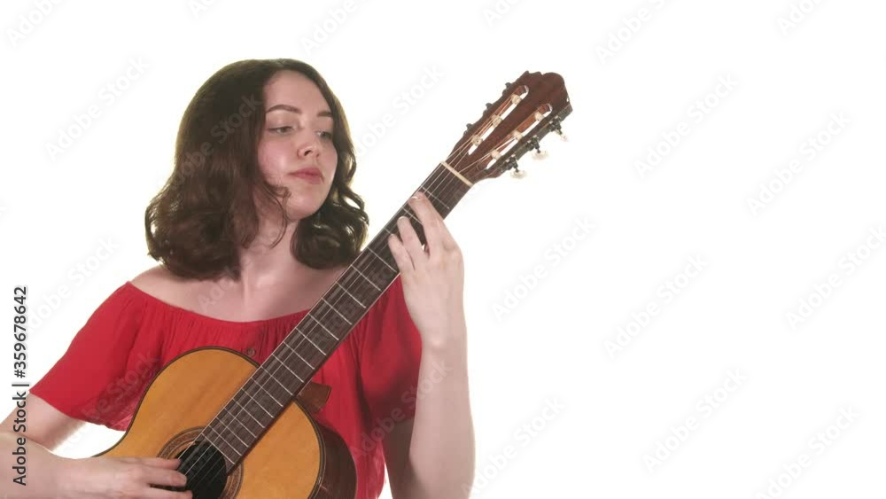 Pretty girl in a red blouse playing the classical acoustic guitar. Medium long shot. Isolated Pretty girl in a red blouse playing the classical acoustic guitar. Medium long shot. Isolated