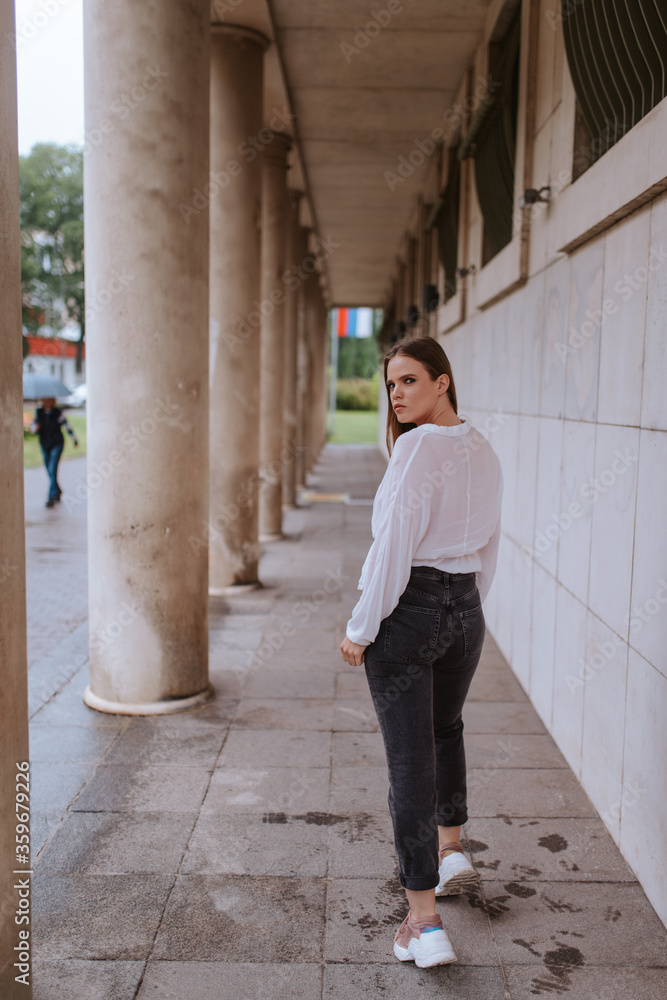 A beautiful young caucasian girl in front of a white building with pillars A beautiful young caucasian girl in front of a white building with pillars