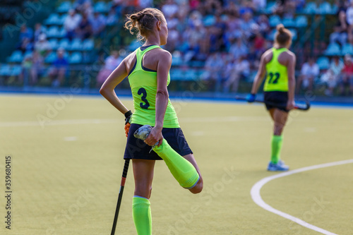 Young woman field hockey player stretching her leg