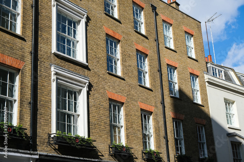 Sunlit brick buildings with shadows on a street in London