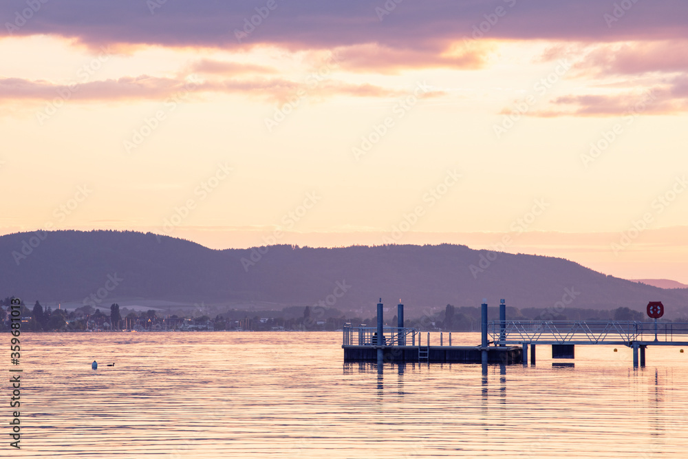 Sunset by the lake. Pier over the water, view on Bodensee, Germany.