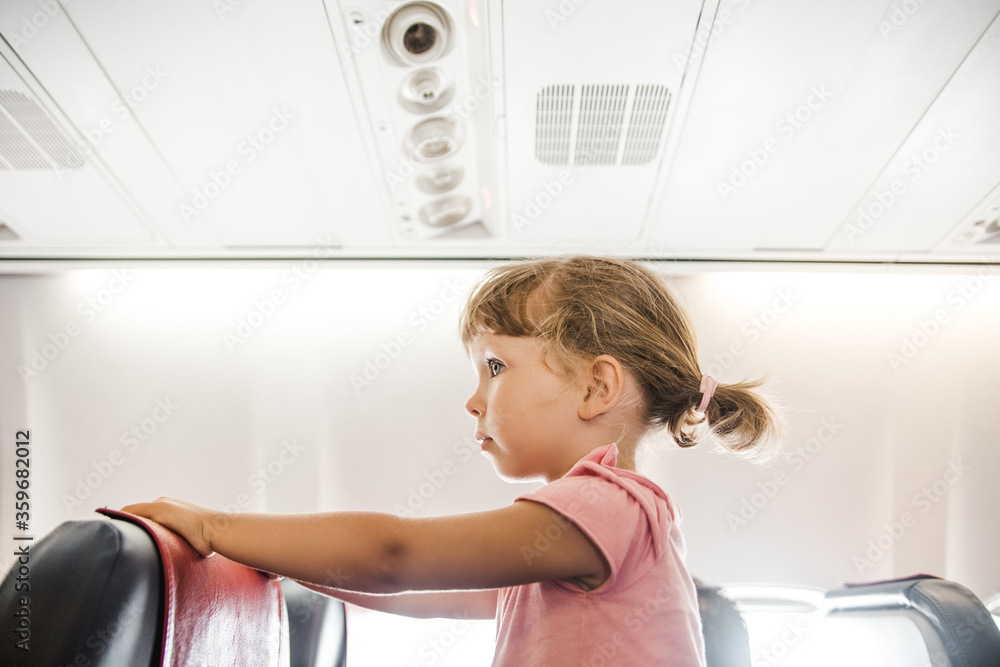 Child girl in an airplane.Cute little girl traveling by an airplane Child girl in an airplane.Cute little girl traveling by an airplane