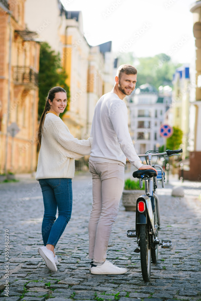 Woman and man with bicycle standing back looking back