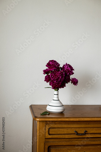 Dark Pink Peony standing in black and white jug on dark brown oak tabletop