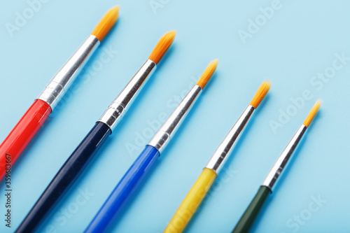 Brushes of different colors for drawing, creativity and art on a blue background.