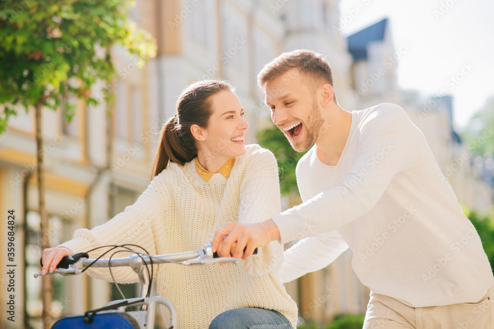 Fototapeta premium Man teaching a joyful woman riding bike