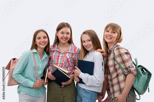 Half length portrait of smiling teenage schoolgirls with backpacks, books and a tablet , isolated photo