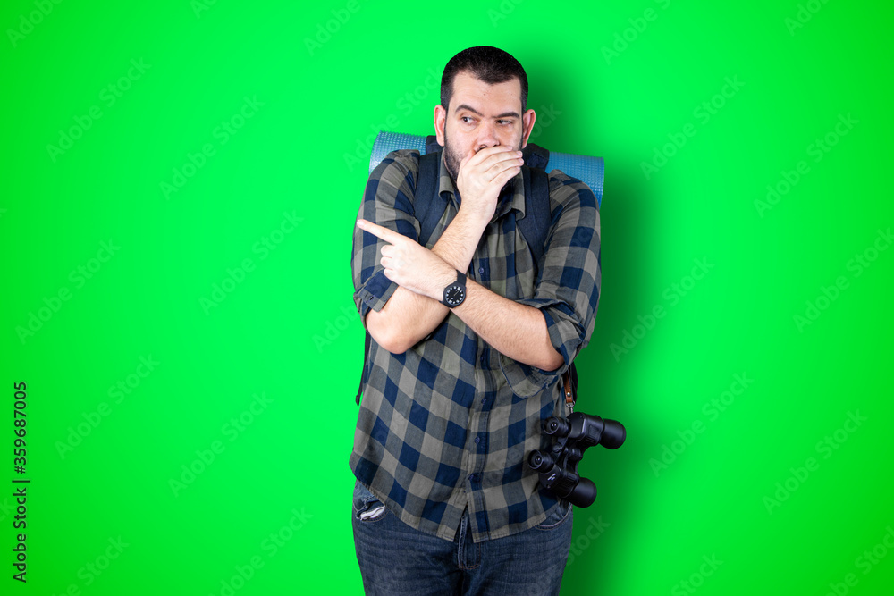 Young traveler man pointing and looking at copy space. Handsome young businessman isolated on green background Young traveler man pointing and looking at copy space. Handsome young businessman isolated on green background