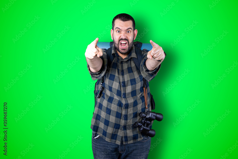 Young traveler man pointing and looking at copy space. Handsome young businessman isolated on green background Young traveler man pointing and looking at copy space. Handsome young businessman isolated on green background