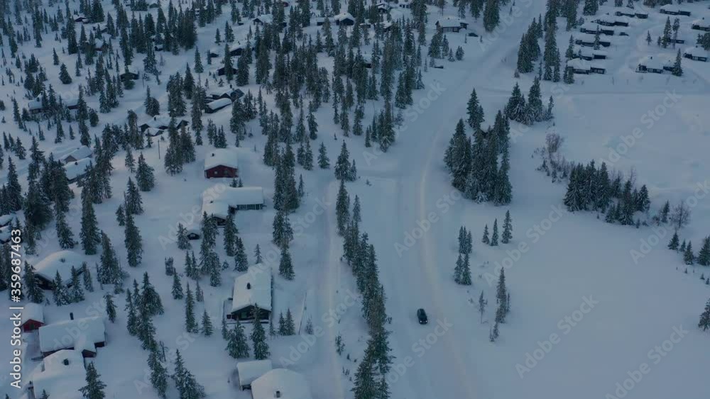 Car driving through snowy scandinavian village on a moody evening. Aerial drone footage 4K. Car driving through snowy scandinavian village on a moody evening. Aerial drone footage 4K.