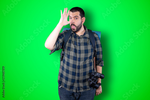 Emotional portrait of a bearded shocked man, amazed funny expression isolated on green background © Carlos Banyuls
