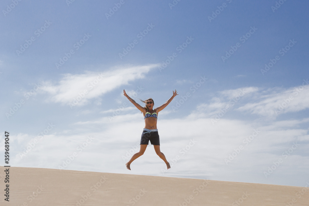 attractive young woman leaps mid air on summer beach