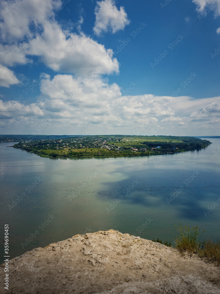High angle, altitude view to the Nistru river, near Dubasari (Dubossary), Transnistria, Moldova. Idyllic vertical orientation scene on the peak of a cliff over the water under a rich blue sky.