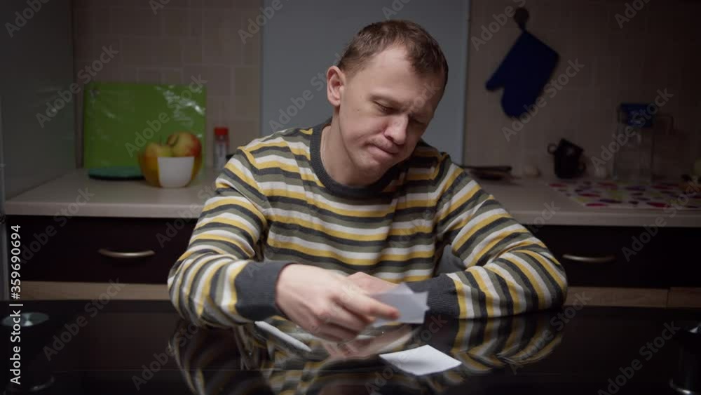 The man is sitting in front of sheets of notes, planning, annoyed tears the records to pieces and throws them up The man is sitting in front of sheets of notes, planning, annoyed tears the records to pieces and throws them up