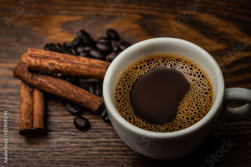 Xícara de café com pau de café e grãos de café sobre a mesa.