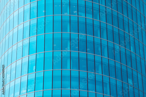 Modern facade of a skyscraper made of glass windows with blue toned.