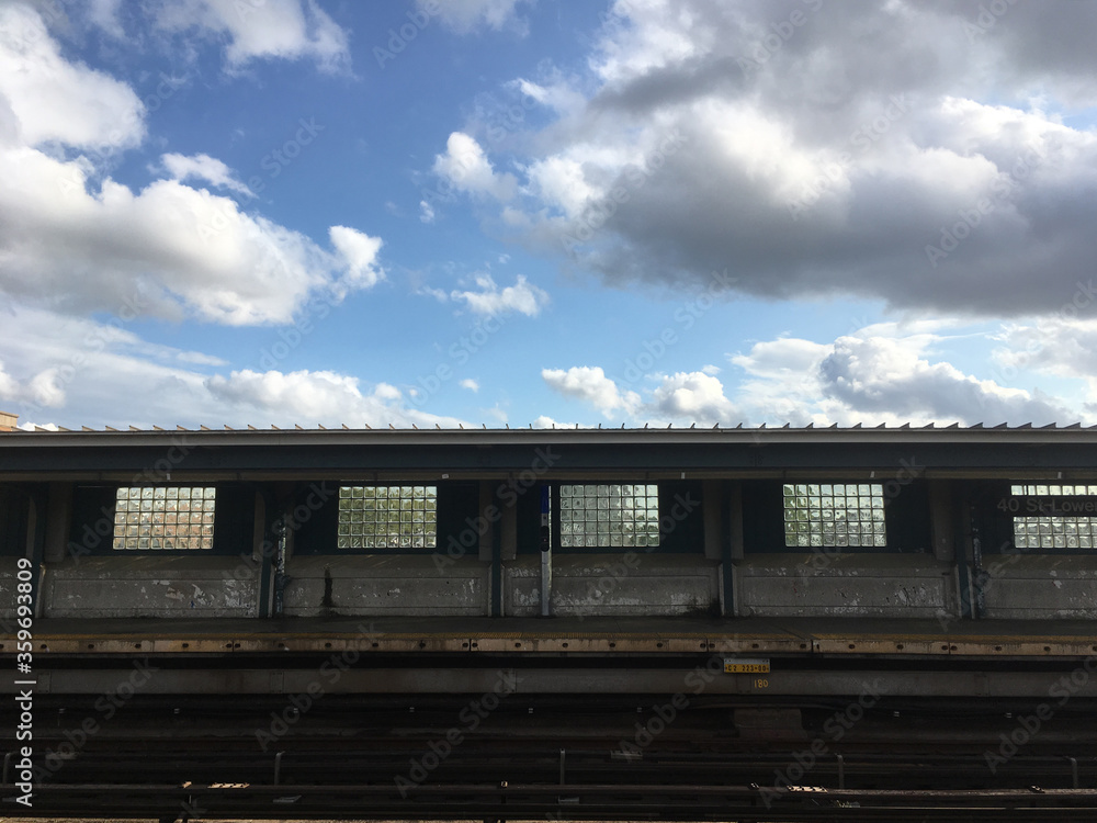 Empty elevated subway platform in New York City. Vacant overground subway station on a bright day with blue skies. Empty train station in Queens New York, room for copy.