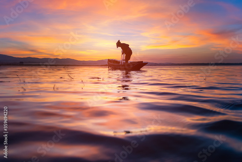 Silhouette of Thailand fisherman on wooden boat . © weerasak